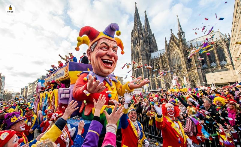 رژه خیابانی کارناوال در شهر کلن آلمان با عروسک‌های بزرگ، لباس‌های مبدل و پرتاب شکلات در مقابل کلیسای جامع کلن